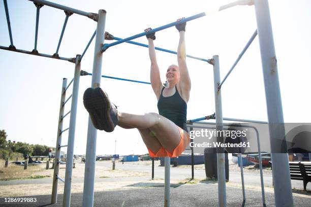 female athlete doing pull ups in outdoor gym on sunny day - doing pull ups stock pictures, royalty-free photos & images
