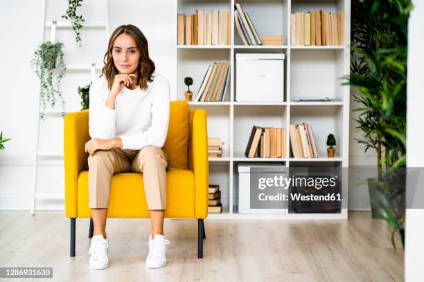 young businesswoman sitting with head in hands on sofa at office - sitting photos et images de collection