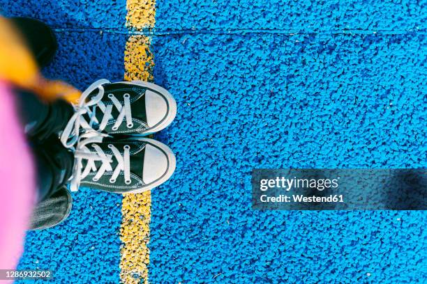 girl standing on yellow line on blue sports court - colorful shoes stock pictures, royalty-free photos & images