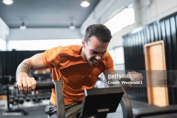 sportsman exercising on exercise equipment in gym - cross trainer stock-fotos und bilder