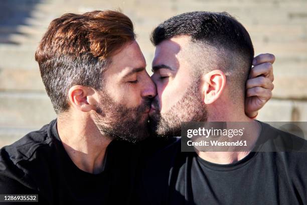 affectionate homosexual couple kissing on sunny day - beso en la boca fotografías e imágenes de stock