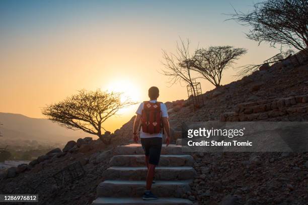 在日落時分徒步旅行時，人爬上山 - ras al khaimah 個照片及圖片檔