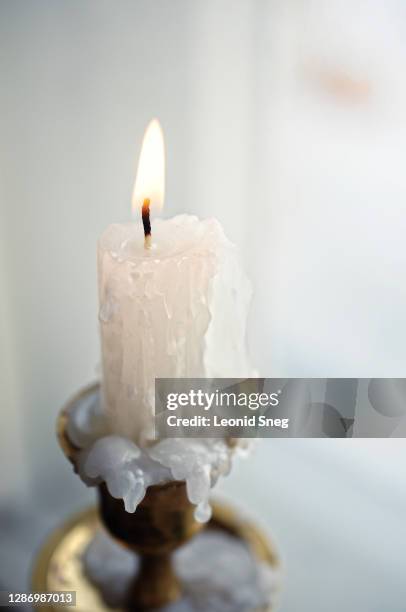 still life with burning white fairy candle side view in a gold candlestick in a bright winter interior on a window background close up - religion symbols stock pictures, royalty-free photos & images