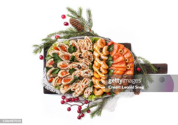 food photography of plate with different festive snacks, appetizers (salmon, shrimp, rolls with red caviar, fish) top view in christmas version with fir branches on white background isolated close up - christmas bbq stock pictures, royalty-free photos & images