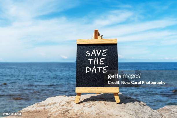 save the date text on a chalkboard at the beach - card board stockfoto's en -beelden