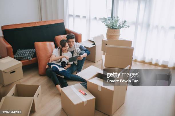 asia chinesische paar sitzen auf dem boden ruhen nach dem öffnen karton kartons im wohnzimmer umzug haus - living room young couple stock-fotos und bilder