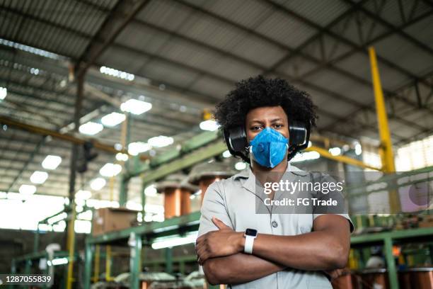 retrato de un hombre confiado de pie con los brazos cruzados en una fábrica - orejeras fotografías e imágenes de stock