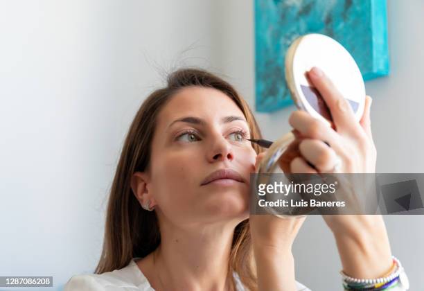 woman doing makeup of eyes at home - delineador fotografías e imágenes de stock