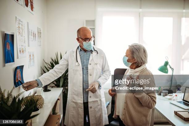 senior doctor showing x-ray to patient - employee engagement mask stock pictures, royalty-free photos & images