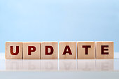 The word Update is written on wooden blocks on a glossy desktop surface on a blue background