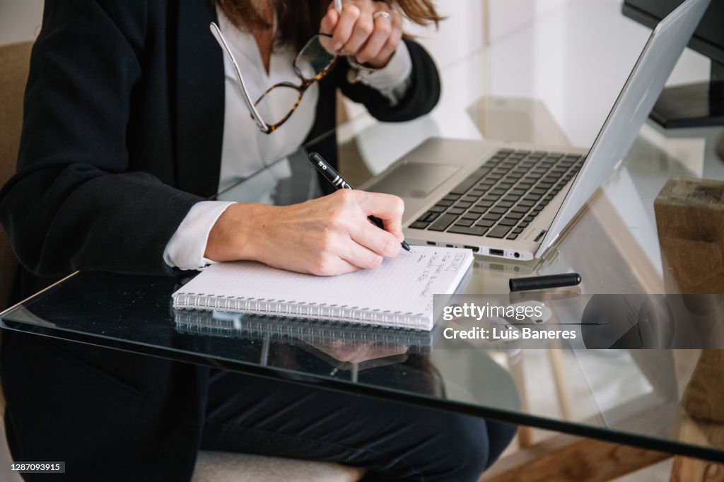 Woman making notes during telework at home