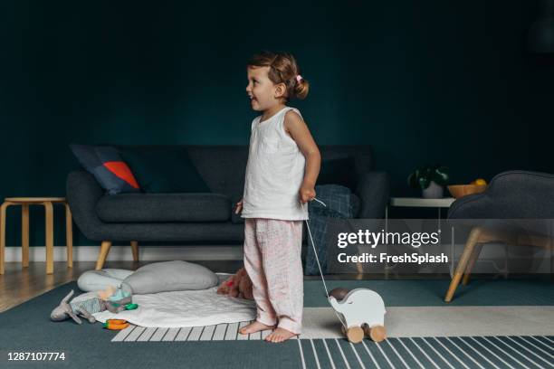 een aanbiddelijk meisje dat met een houten olifant in de woonkamer speelt - elephant at home stockfoto's en -beelden