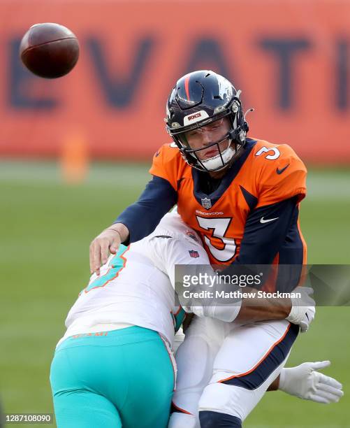 Drew Lock of the Denver Broncos is hit by Kyle Van Noy of the Miami Dolphins as he throws during the second quarter at Empower Field At Mile High on...
