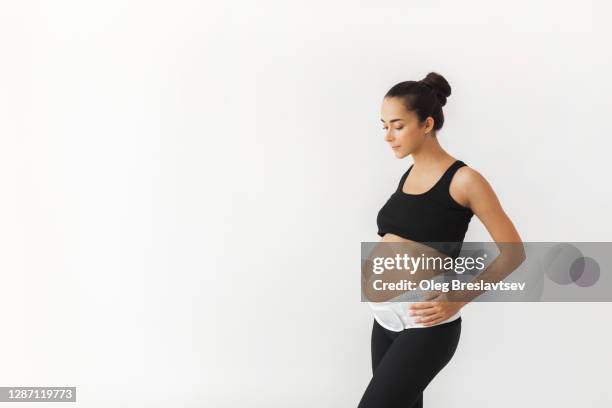 pregnant tired woman with naked abdomen in support bandage medical corset. - orthopedic corset stock pictures, royalty-free photos & images