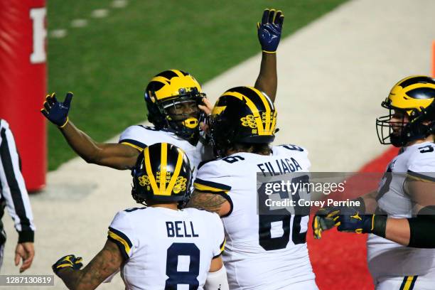 Mike Sainristil of the Michigan Wolverines celebrates his touchdown with teammates Chuck Filiaga and Ronnie Bell during the fourth quarter at SHI...