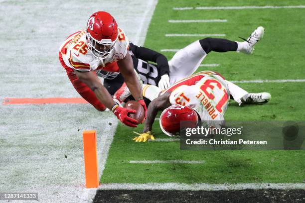 Running back Clyde Edwards-Helaire of the Kansas City Chiefs dives into the end zone for a touchdown past the defense of strong safety Jeff Heath of...