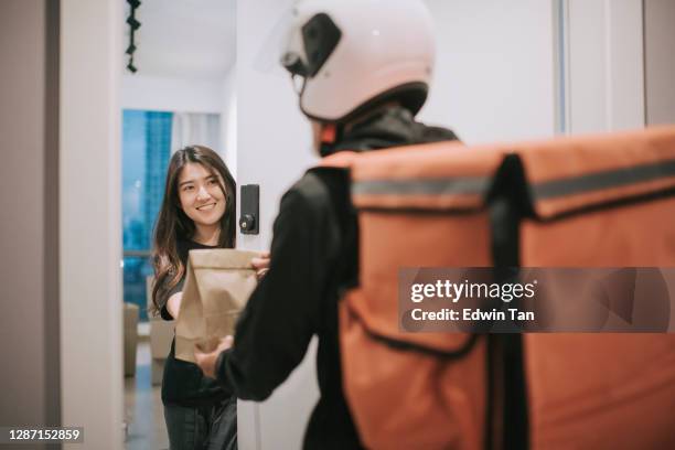 asiatische chinesische liefermann mit helm drücken türglocke für lebensmittel lieferung - food to go stock-fotos und bilder