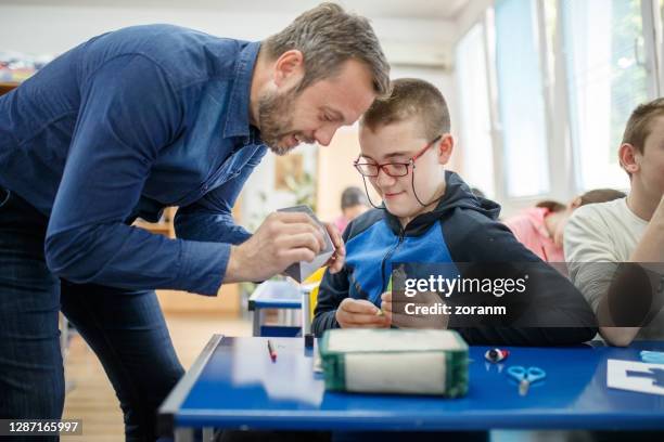 leraar speciaal onderwijs van aangezicht tot aangezicht met intellectuele disabiled jongen - special needs stockfoto's en -beelden