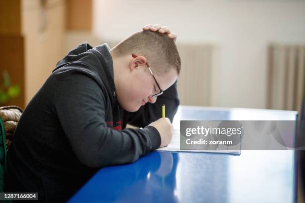 speciale behoeften jongen die in zijn notitieboekje trekt - special needs stockfoto's en -beelden