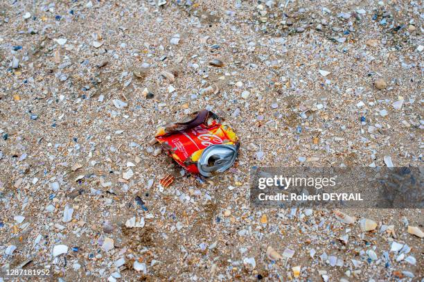 Une canette de soda Coca-Cola écrasée au milieu des débris de coquillages sur le sable de la plage le 8 juillet 2016 à Deauville, Calvados, France.