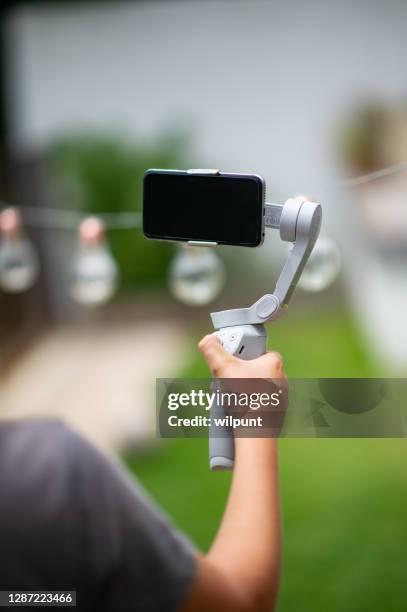 dji om4 smartphone gimbal mit jungen arm hält es mit lichterketten hintergrund für vlogging - hand iphone selfie stock-fotos und bilder