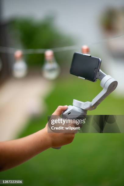 dji om4 smartphone gimbal mit jungen hand hält es mit lichterketten hintergrund für vlogging - hand iphone selfie stock-fotos und bilder