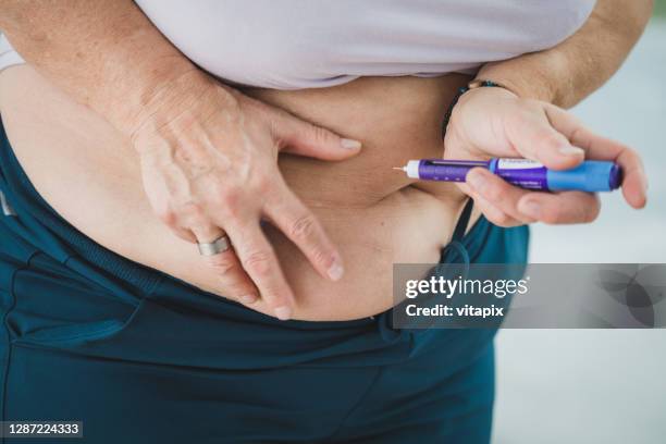 overweight woman receiving an insulin shot - injecting stomach stock pictures, royalty-free photos & images