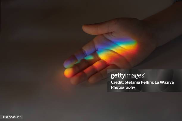 kid's hand catching a rainbow - rainbow kids stock-fotos und bilder