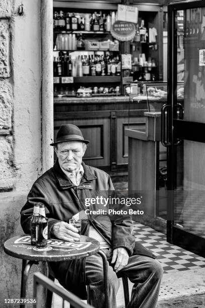 ein älterer mann sitzt vor einer bar im stadtteil trastevere in rom - italy beer stock-fotos und bilder