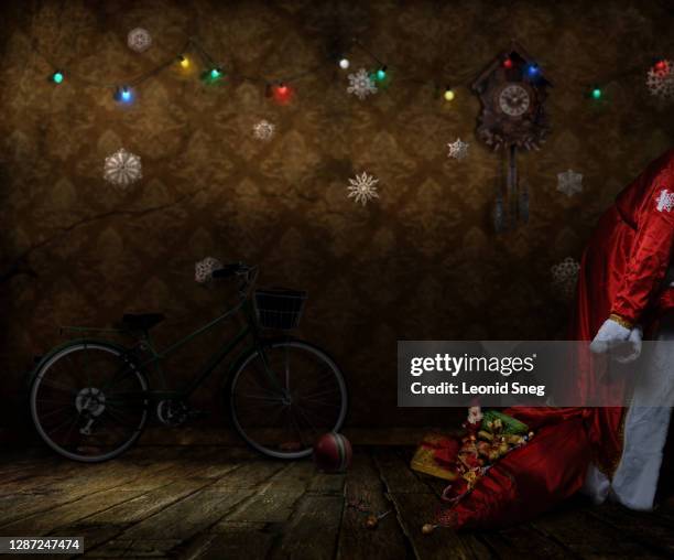 santa claus front view with a bag from which gifts fall sneaking in a room house in retro style with new year decorations on the wall close up - santa close up stock-fotos und bilder