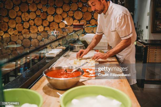 pizza chef preparing a pizza at the restaurant - pizza chef stock pictures, royalty-free photos & images