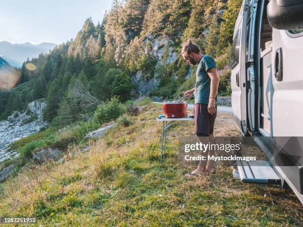 mann kocht auf tragbarem grill vor seinem van, bergblick - camper van stock-fotos und bilder