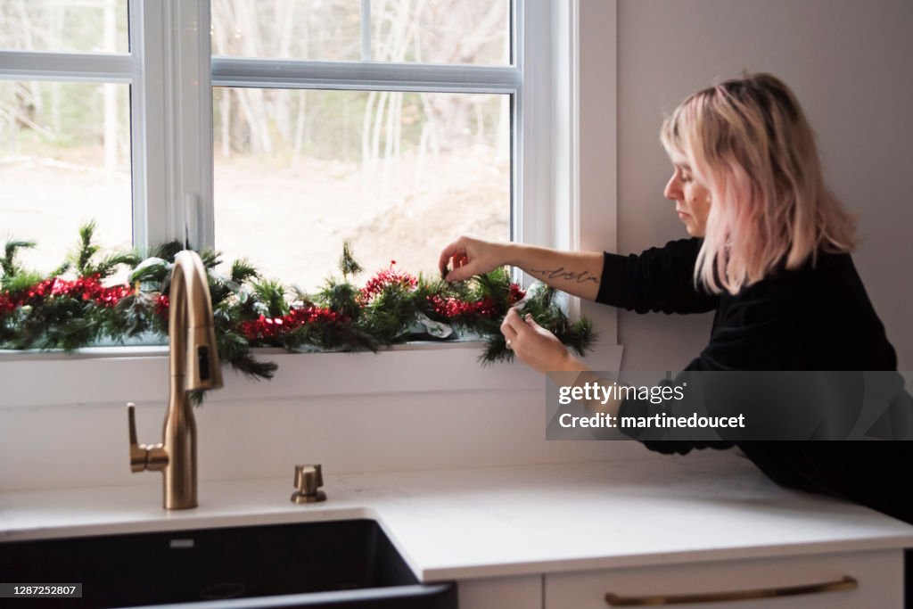 クリスマスのための台所の窓を飾る女性。