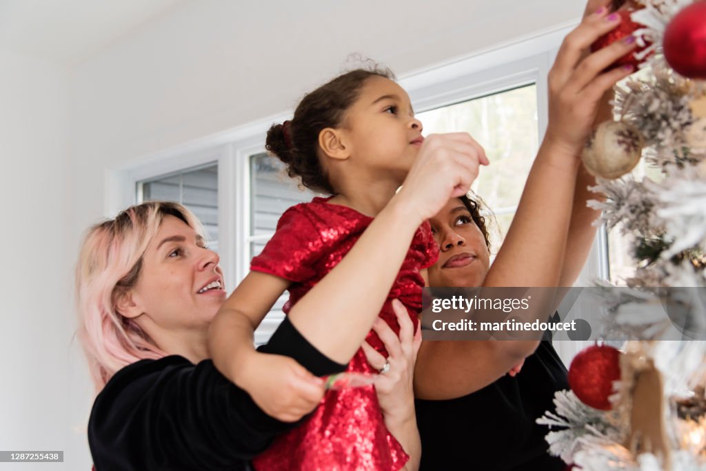 Familia de raza mixta que decora el árbol de Navidad.