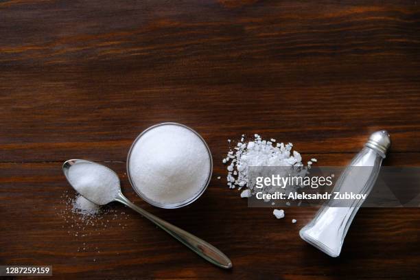 natural, organic, sea, white salt in a spoon, in a cup, in a salt shaker, poured on a wooden table. the concept of cooking healthy food, cosmetology. selective focus - sel minéraux photos et images de collection