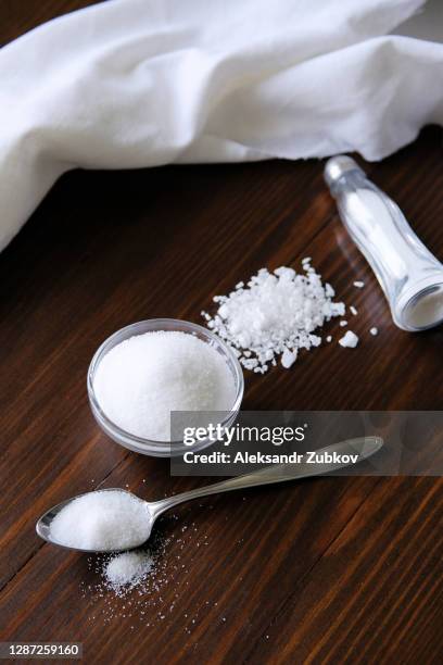 natural, organic, sea, white salt in a spoon, in a cup, in a salt shaker, poured on a wooden table. next to the linen towel. the concept of cooking healthy food, cosmetology. selective focus - zout smaakstof stockfoto's en -beelden