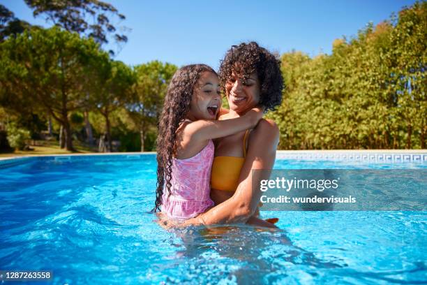 hija en la vuelta de la madre dentro de la piscina en el verano - niño bañandose fotografías e imágenes de stock