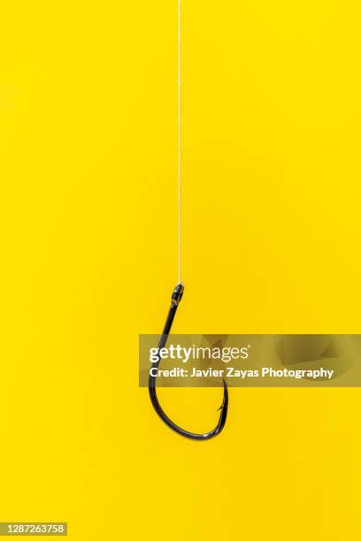 fishing hook on yellow background - angel stock-fotos und bilder
