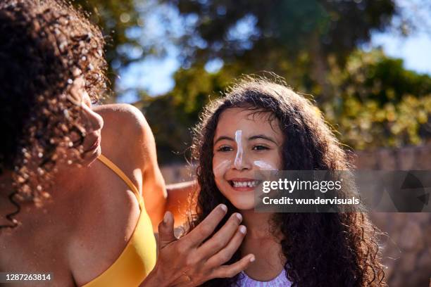 mother putting sunscreen on daughter in the summer - putting lotion stock pictures, royalty-free photos & images