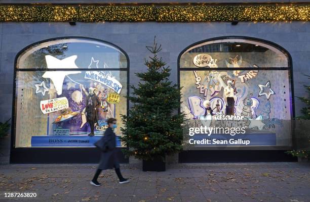 Woman wearing a protective face mask walks past Christmas display windows of KaDeWe department store during the second wave of the coronavirus...