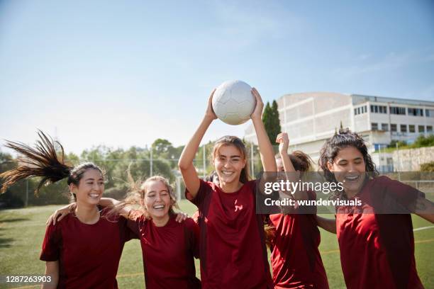 female soccer player looking at camera celebrating goal with teammates - youth football team stock pictures, royalty-free photos & images