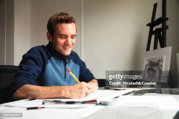 close-up of a trans male artist smiling as he draws at his workshop table - autism stock pictures, royalty-free photos & images