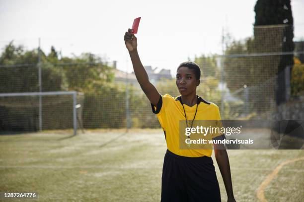 arbitro mujer afroamericana sosteniendo tarjeta roja en uniforme amarillo - poder fotografías e imágenes de stock