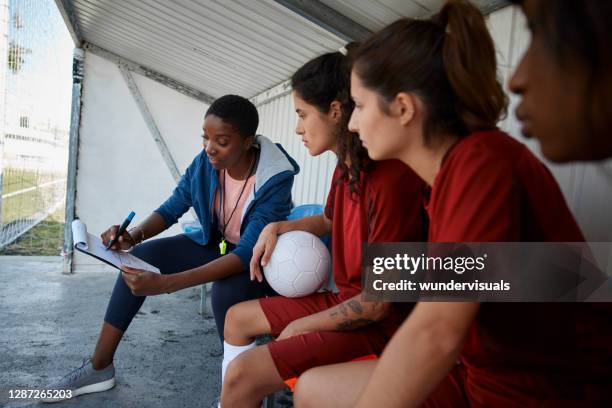 entrenador de fútbol explicando estrategias de partido a su equipo de fútbol femenino - banco de jogadores fotografías e imágenes de stock