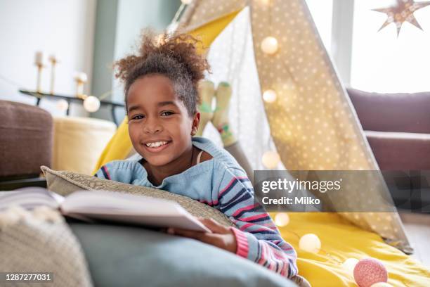 a little african american girl is reading a book at home - development camp stock pictures, royalty-free photos & images