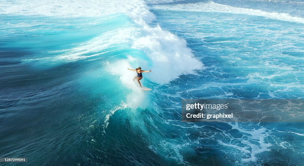 Mujer surfista montando en el océano azul