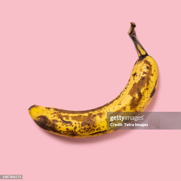 overripe banana on pink background - fruit decay stockfoto's en -beelden