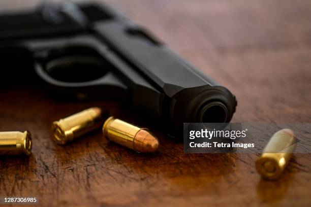 gold bullets and pistol on wooden surface - crime and murder stockfoto's en -beelden