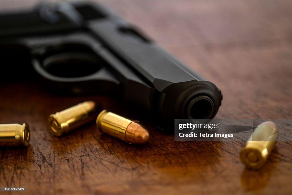 Gold bullets and pistol on wooden surface