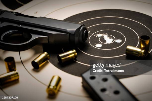 gun and ammo on target - sportschießen stock-fotos und bilder